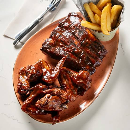 A platter of BBQ ribs and chicken wings with chips